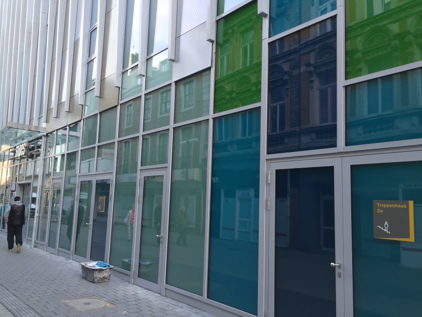 An zwei Stellen kann man das Gebäude betreten, der Rest sieht etwas abweisend aus. Schade, dass man dort die Läden nicht auch nach außen geöffnet hat, nur nach innen. 